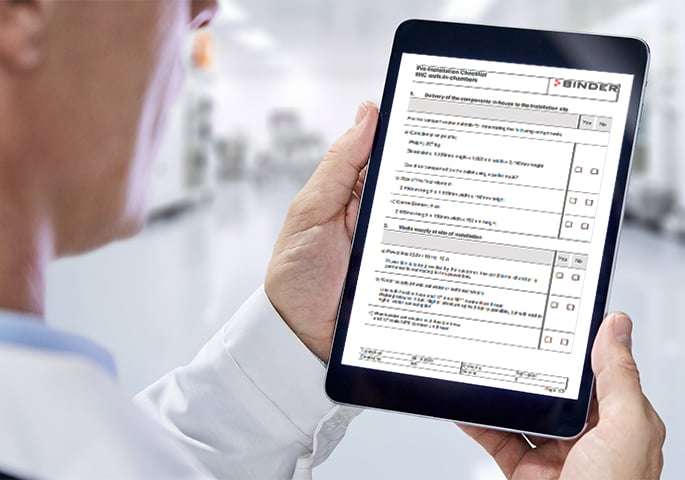 Person hält ein Tablet mit der BINDER Pre-Installation-Checkliste für Walk-in-Chambers